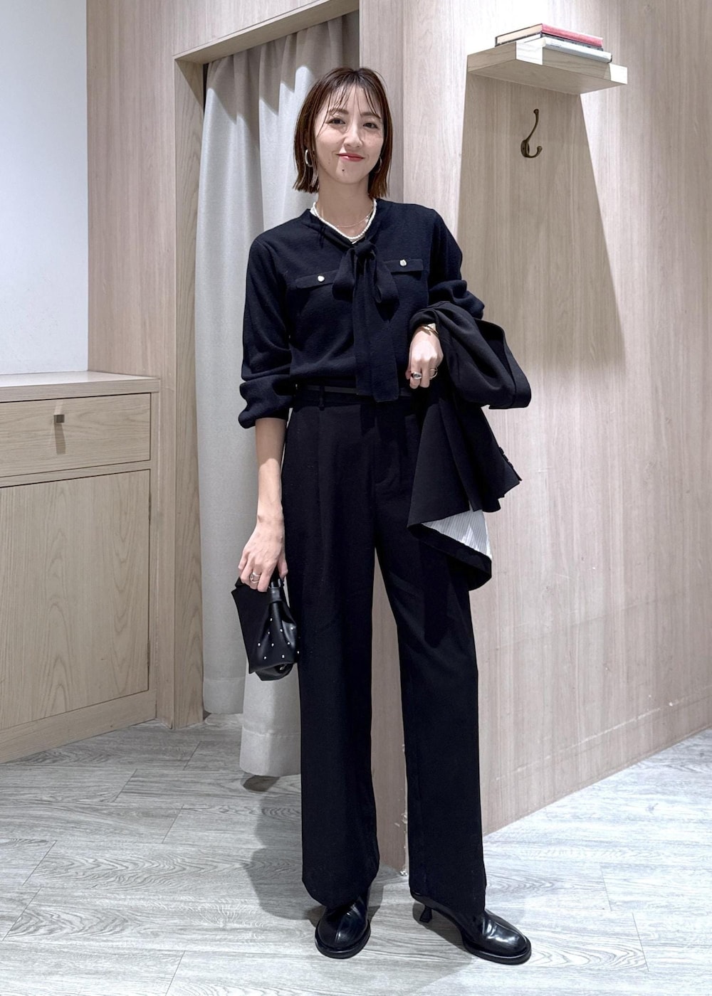 ブラック系のスラックス、ブラック系のテーラードジャケット、ブラック系のショルダーバッグを着用したレディースの冬コーディネートの2枚目の写真