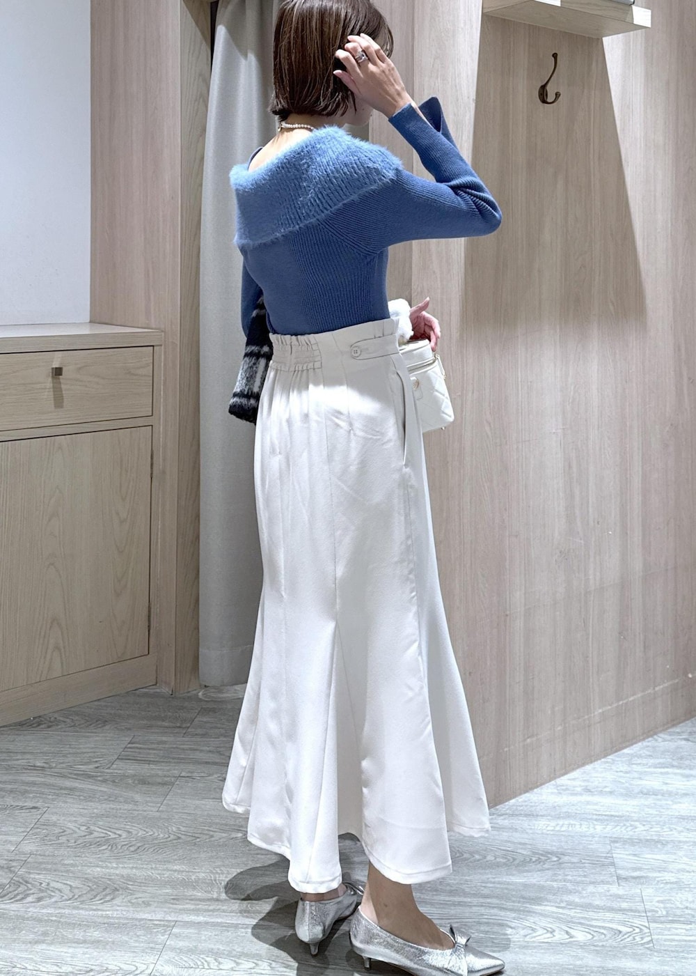 シルバー系のパンプス、ホワイト系のハンドバッグ、ブルー系のニット/セーターを着用したレディースの秋コーディネートの3枚目の写真