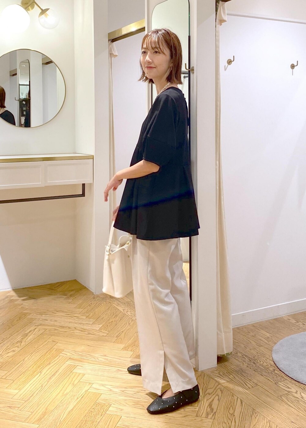 ホワイト系のショルダーバッグ、ホワイト系のスラックス、ブラック系のバレエシューズを着用したレディースの秋コーディネートの2枚目の写真