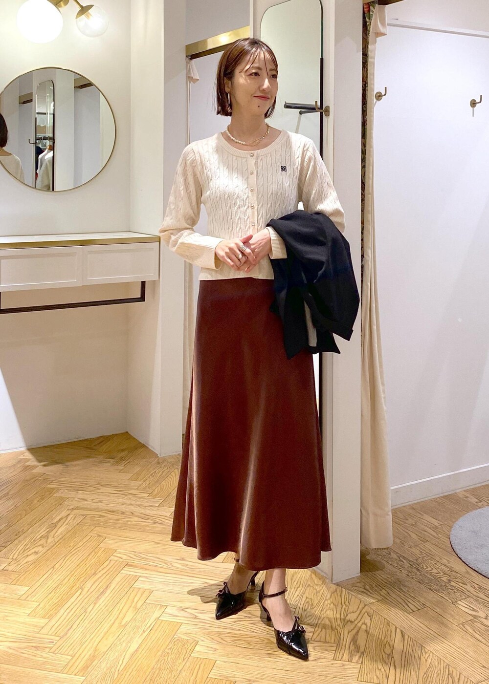 ブラック系のテーラードジャケット、ブラック系のパンプス、ブラウン系のスカートを着用したレディースの冬コーディネートの7枚目の写真