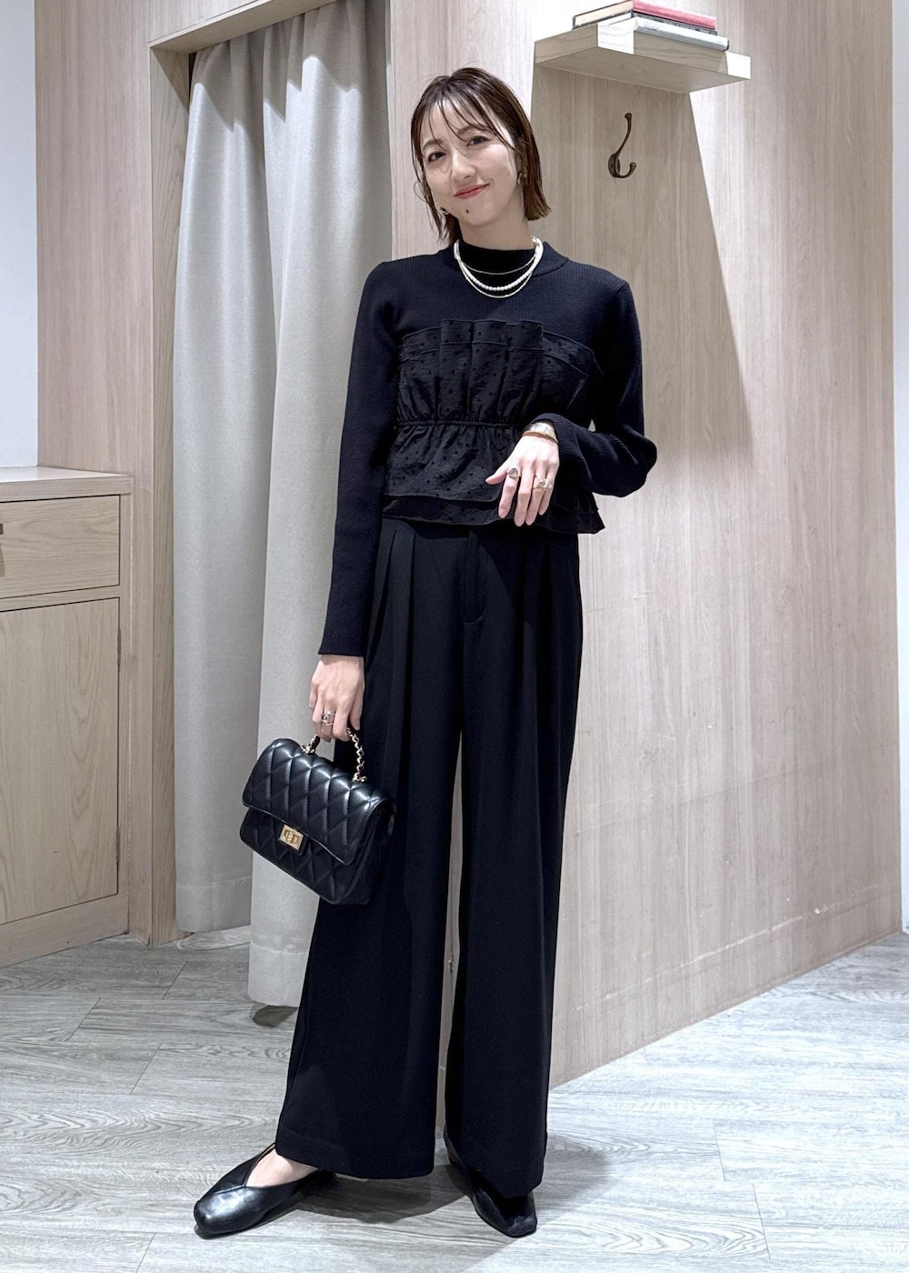 ブラック系のその他パンツ、ブラック系のニット/セーター、ブラック系のショルダーバッグを着用したレディースの冬コーディネートの2枚目の写真