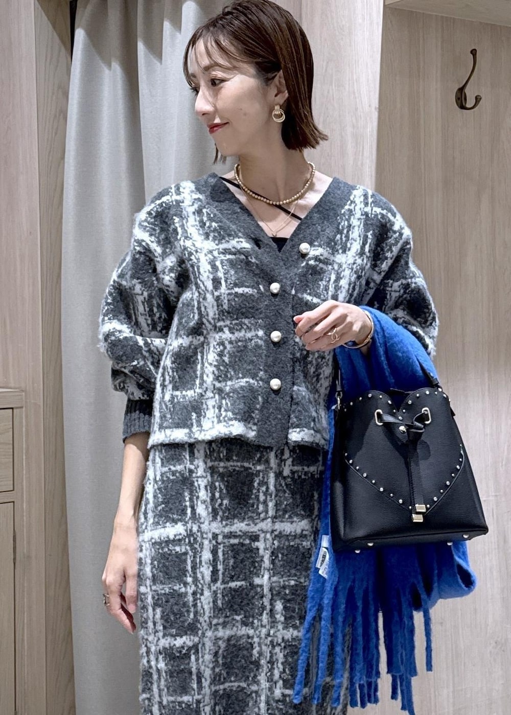 グレー系のスカート、グレー系のカーディガン/ボレロ、ブラック系のショルダーバッグを着用したレディースの冬コーディネートの5枚目の写真