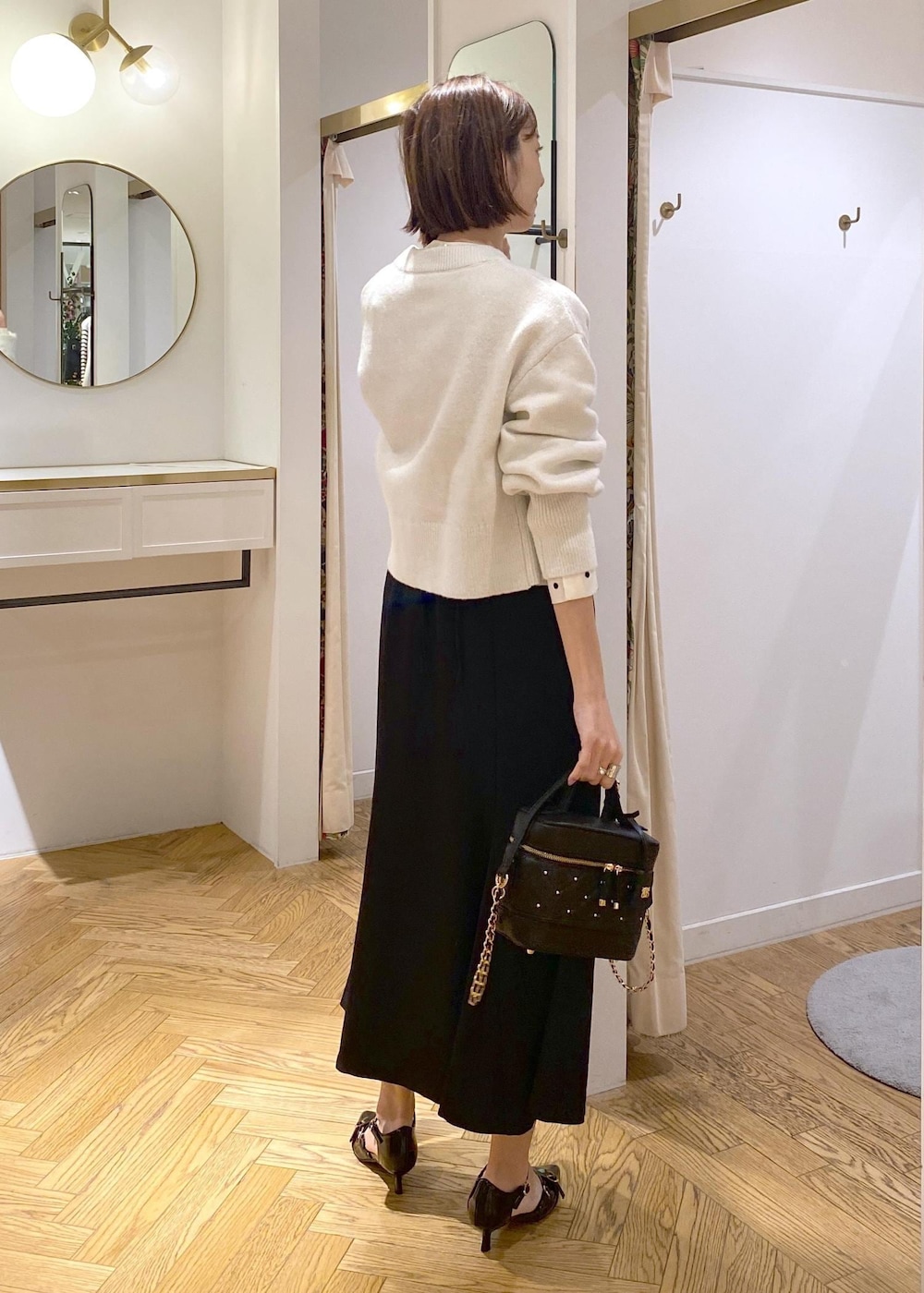 ホワイト系のカーディガン/ボレロ、ブラック系のスカート、ブラック系のパンプスを着用したレディースの冬コーディネートの3枚目の写真