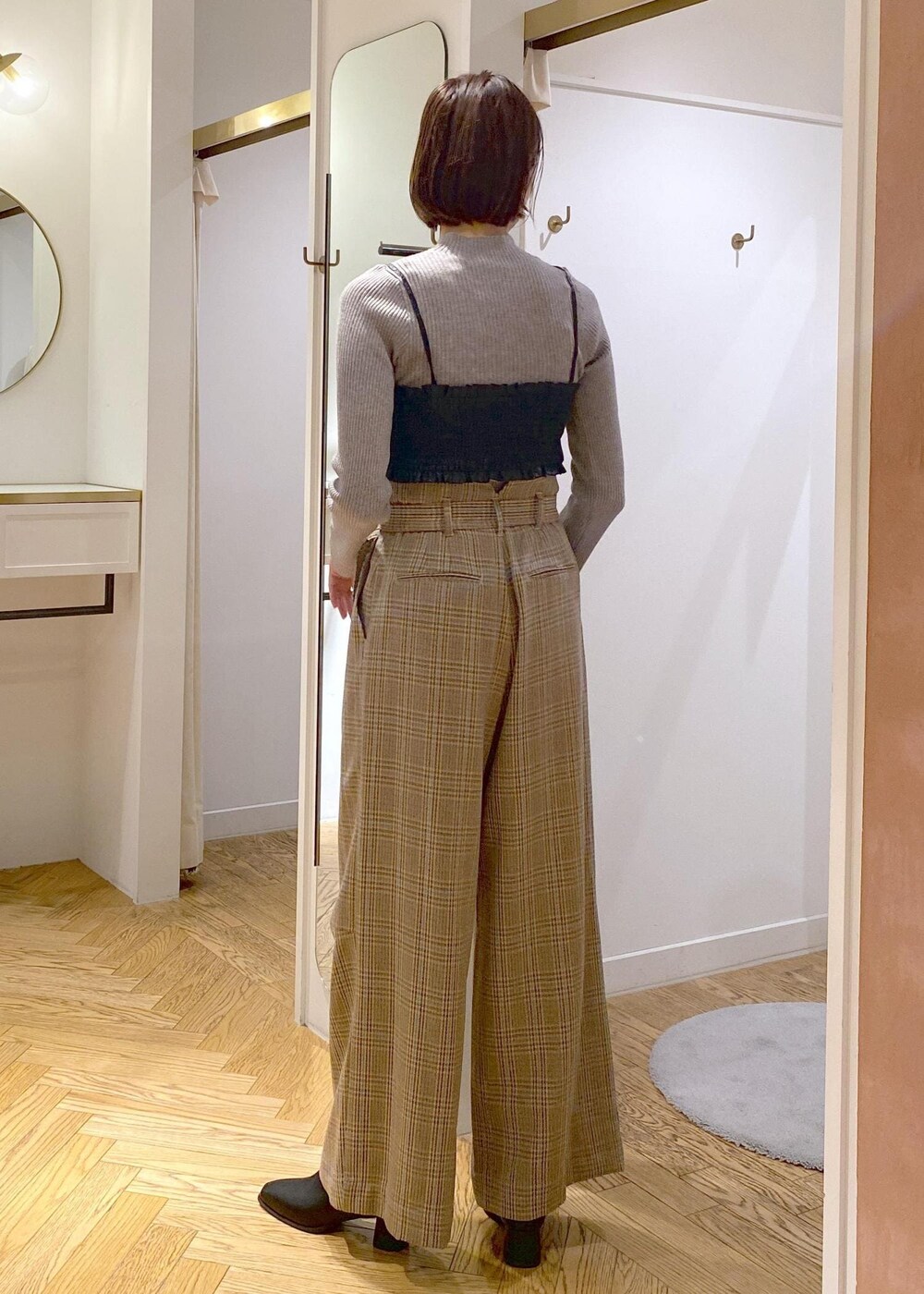 ブラック系のショルダーバッグ、ブラック系のブーツ、ベージュ系のスラックスを着用したレディースの秋コーディネートの4枚目の写真