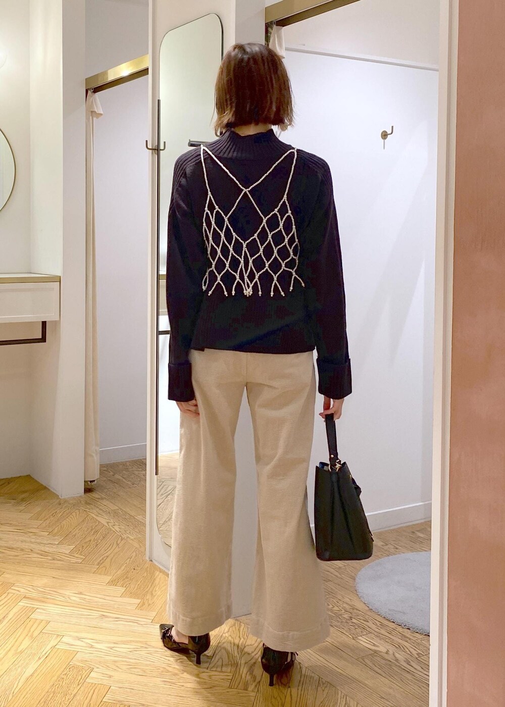 ブラック系のショルダーバッグ、ホワイト系のキャミソール、ベージュ系のスラックスを着用したレディースの秋コーディネートの3枚目の写真