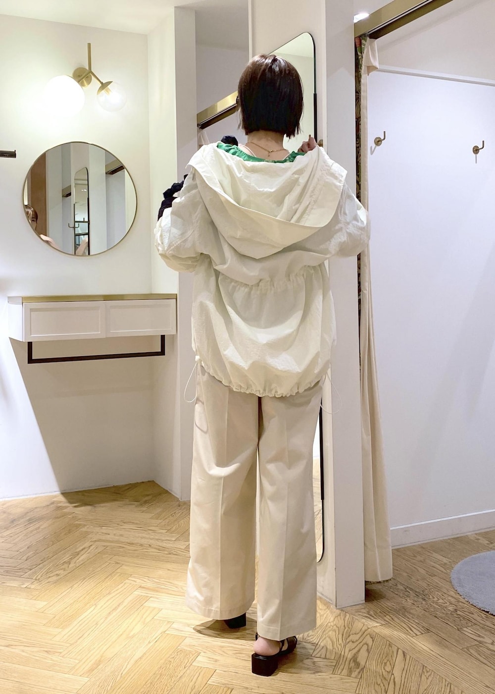 ホワイト系のスラックス、ホワイト系のマウンテンパーカー、ブラック系のサンダルを着用したレディースの春コーディネートの3枚目の写真