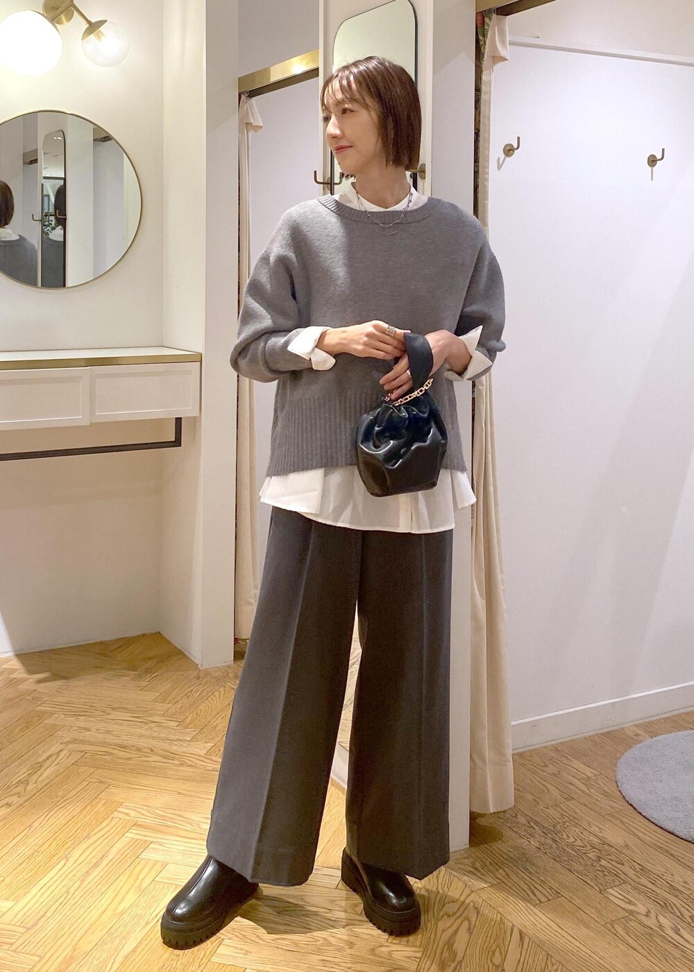 ブラック系のブーツ、ホワイト系のシャツ/ブラウス、グレー系のニット/セーターを着用したレディースの冬コーディネートの3枚目の写真