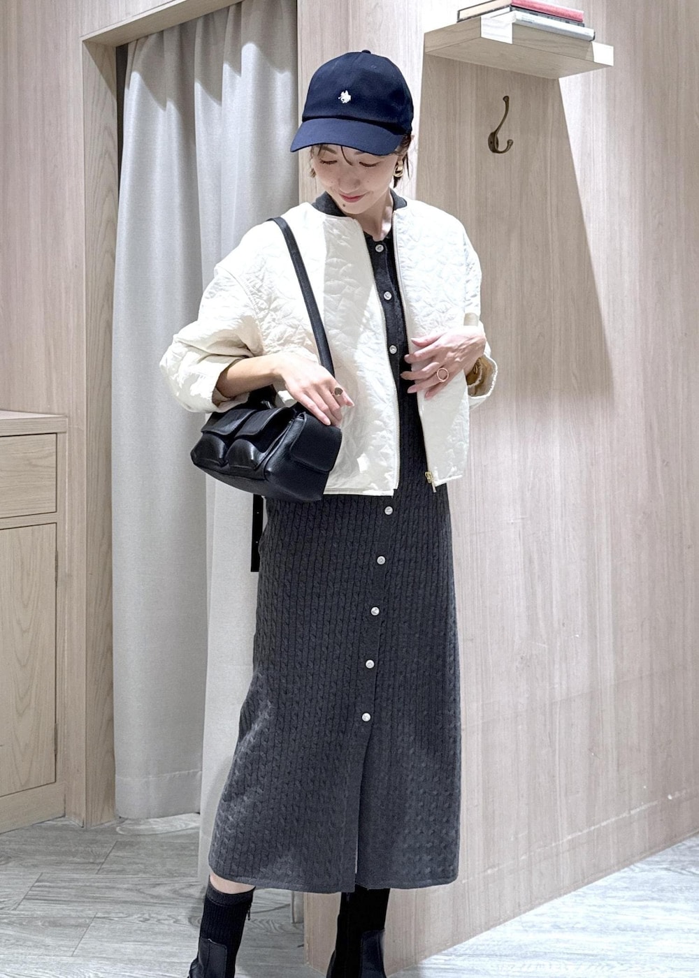 ブラック系のショルダーバッグ、ブラック系のブーツ、ホワイト系のブルゾンを着用したレディースの秋コーディネートの3枚目の写真