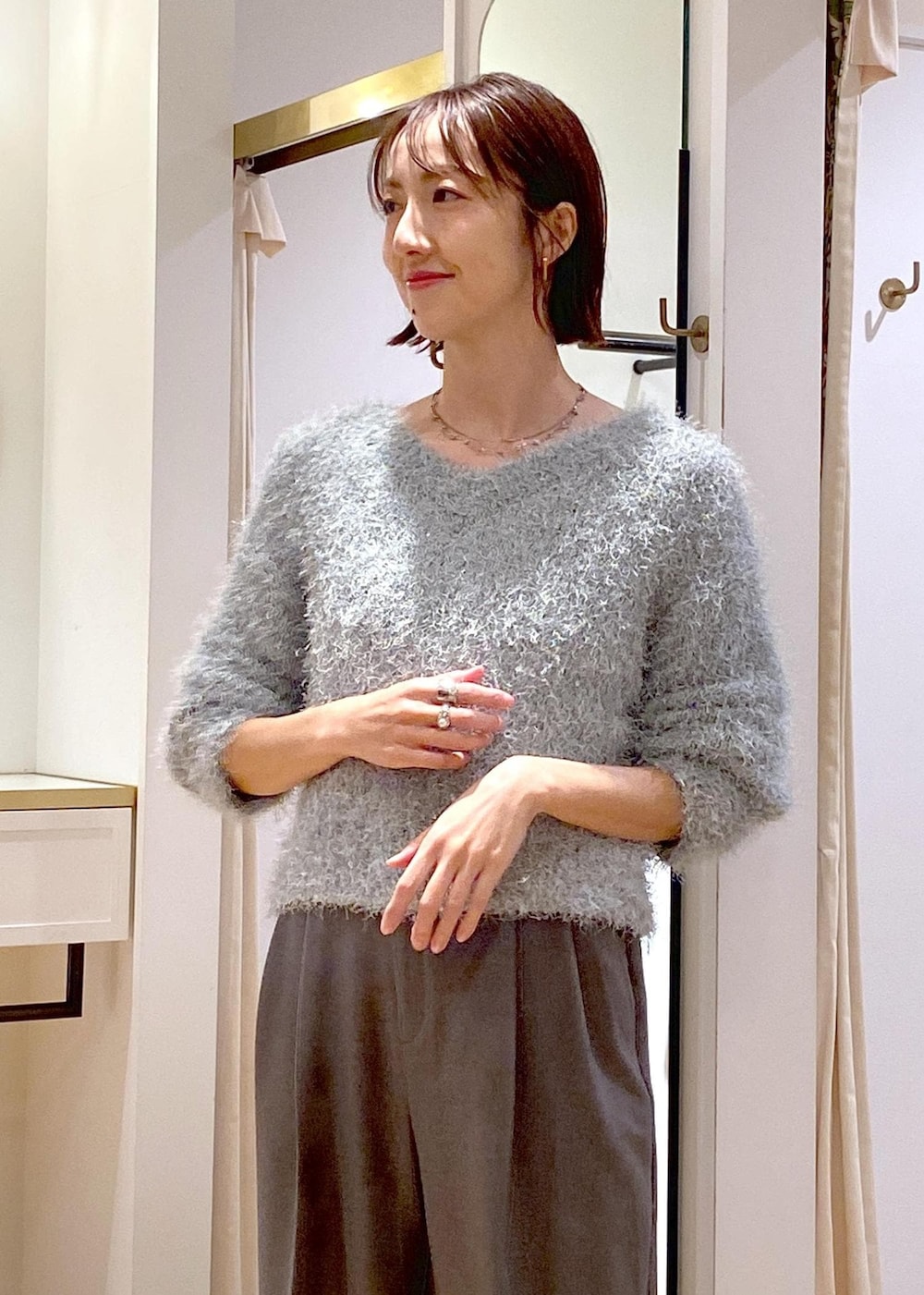 グレー系のスラックス、ブルー系のショルダーバッグ、ブラック系のパンプスを着用したレディースの冬コーディネートの9枚目の写真