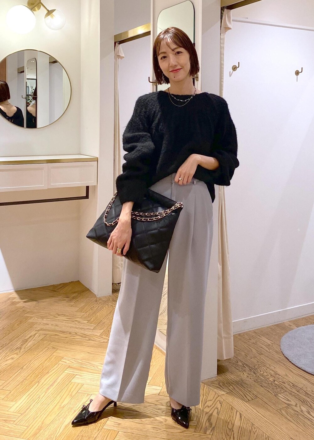 ブルー系のスラックス、ブラック系のパンプス、ブラック系のショルダーバッグを着用したレディースの冬コーディネートの4枚目の写真