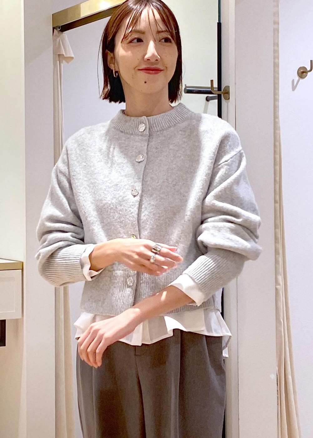 ホワイト系のブーツ、ホワイト系のシャツ/ブラウス、グレー系のカーディガン/ボレロを着用したレディースの冬コーディネートの6枚目の写真