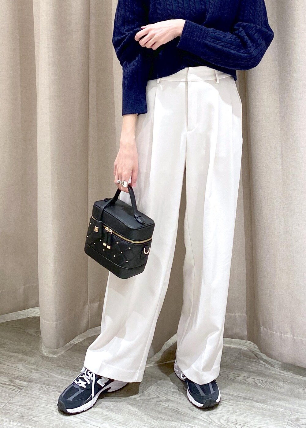 ブラック系のキャミソール、ブラック系のハンドバッグ、ホワイト系のスラックスを着用したレディースの冬コーディネートの6枚目の写真