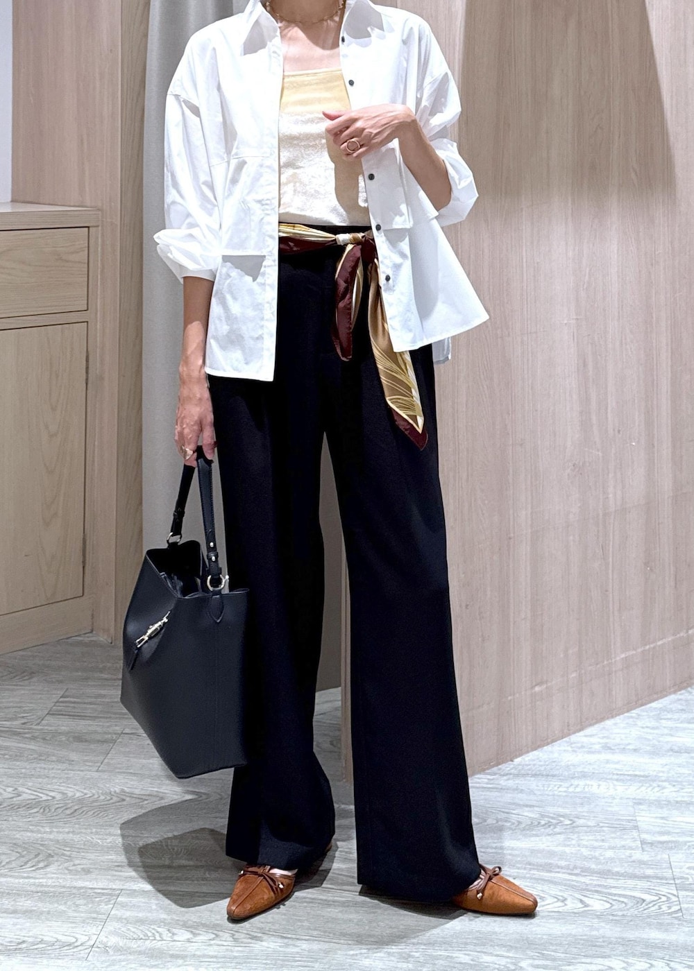 ブラック系のトートバッグ、イエロー系のパンプス、ホワイト系のシャツ/ブラウスを着用したレディースの秋コーディネートの6枚目の写真