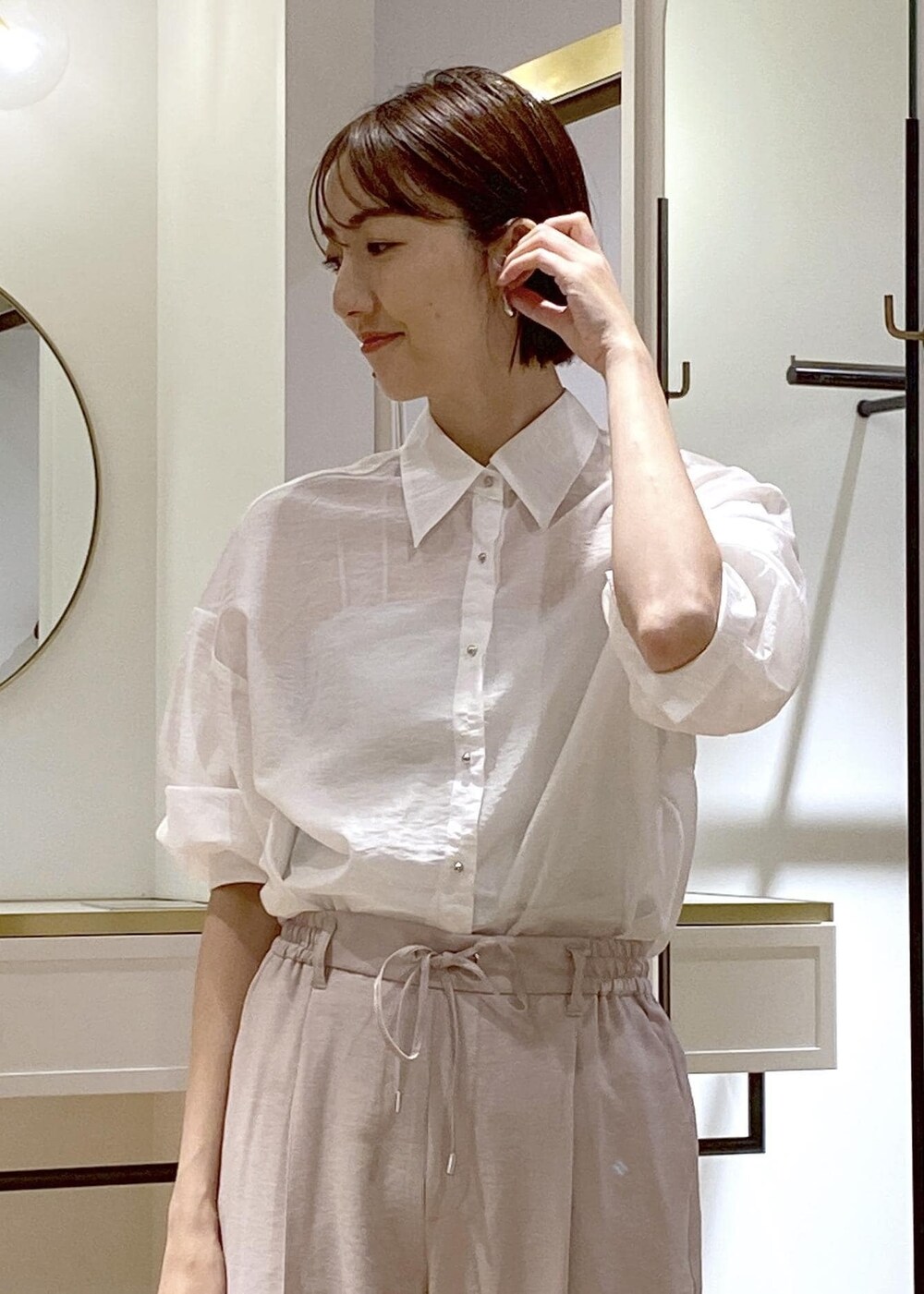 ブラック系のパンプス、ブラック系のハンドバッグ、ホワイト系のスラックスを着用したレディースの夏コーディネートの5枚目の写真