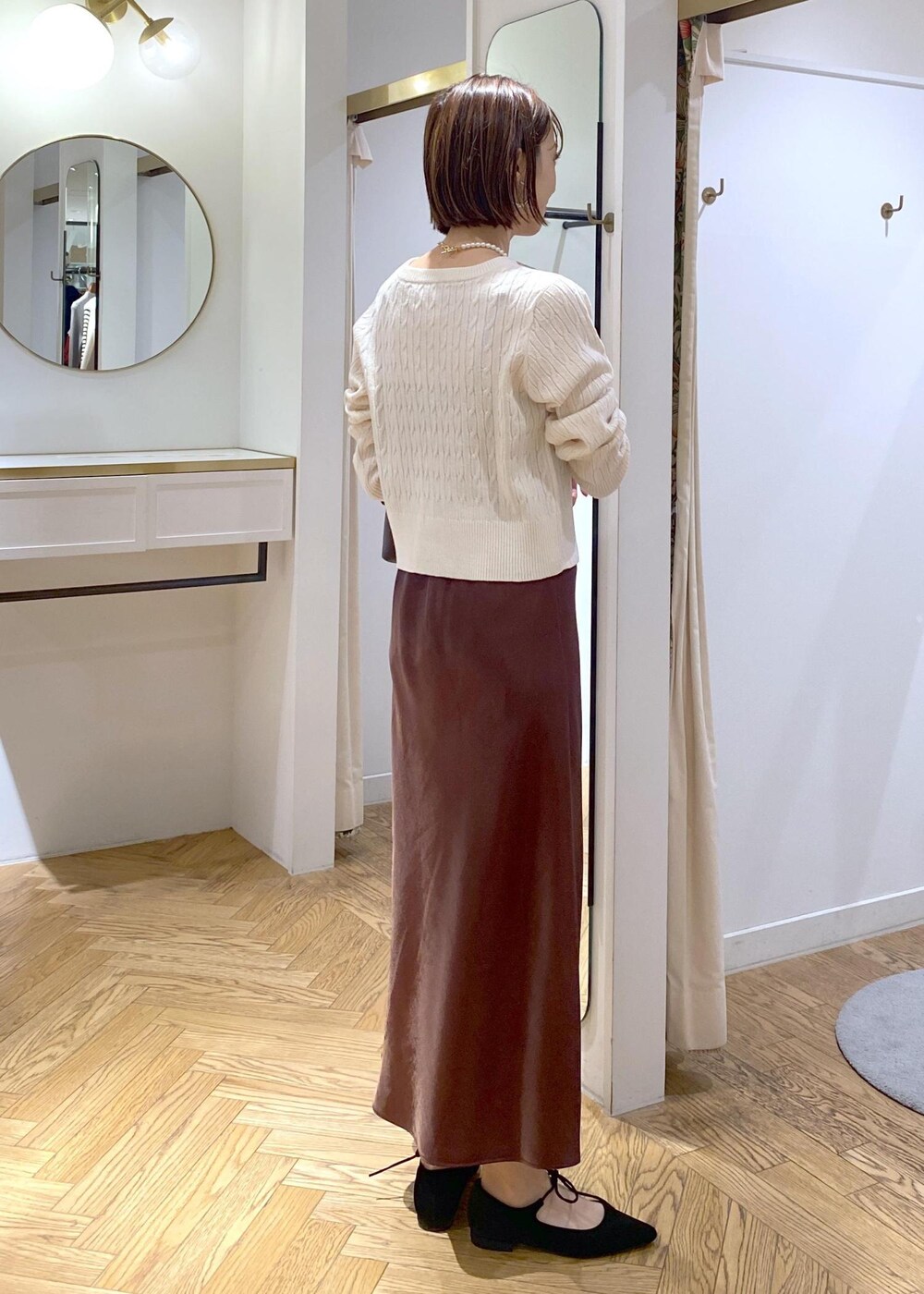 ブラウン系のスカート、ホワイト系のカーディガン/ボレロ、ブラック系のパンプスを着用したレディースの冬コーディネートの3枚目の写真