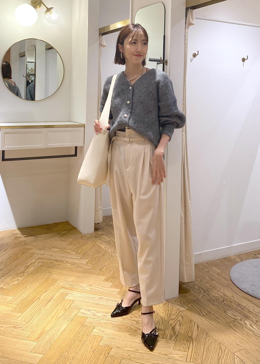 ホワイト系のトートバッグ、ブラック系のパンプス、ベージュ系のその他パンツを着用したレディースの冬コーディネートの3枚目の写真