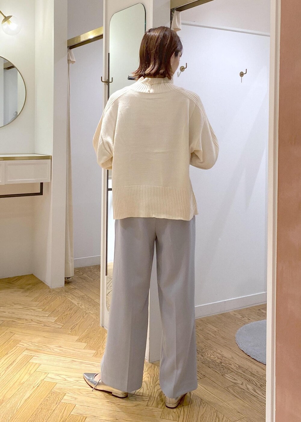 シルバー系のパンプス、ブラック系のショルダーバッグ、ブルー系のスラックスを着用したレディースの秋コーディネートの3枚目の写真