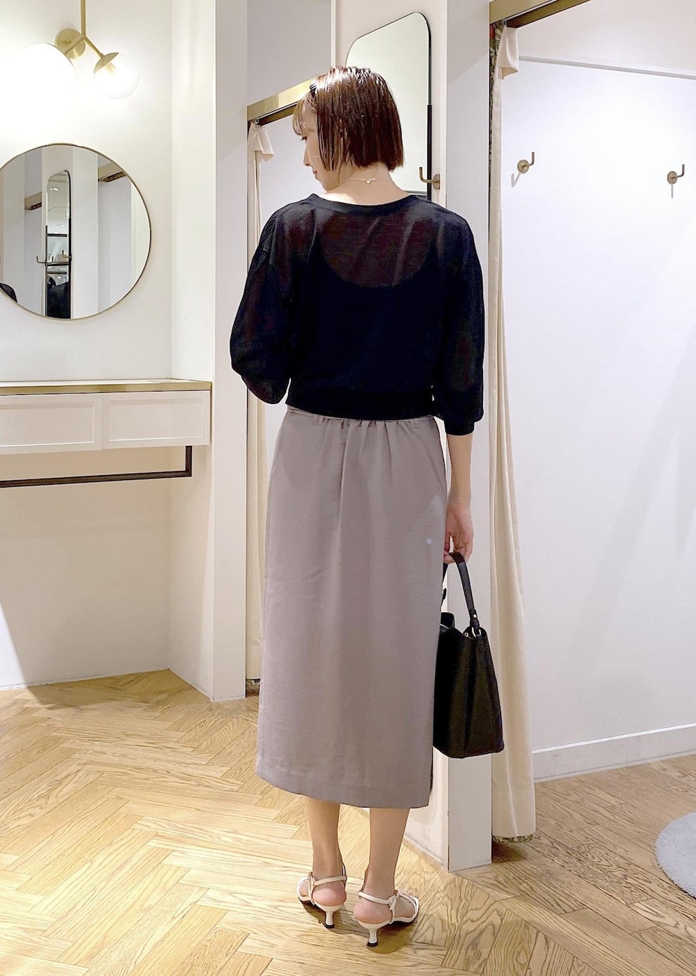 ブラック系のキャミソール、ブラック系のハンドバッグ、ホワイト系のサンダルを着用したレディースの夏コーディネートの2枚目の写真