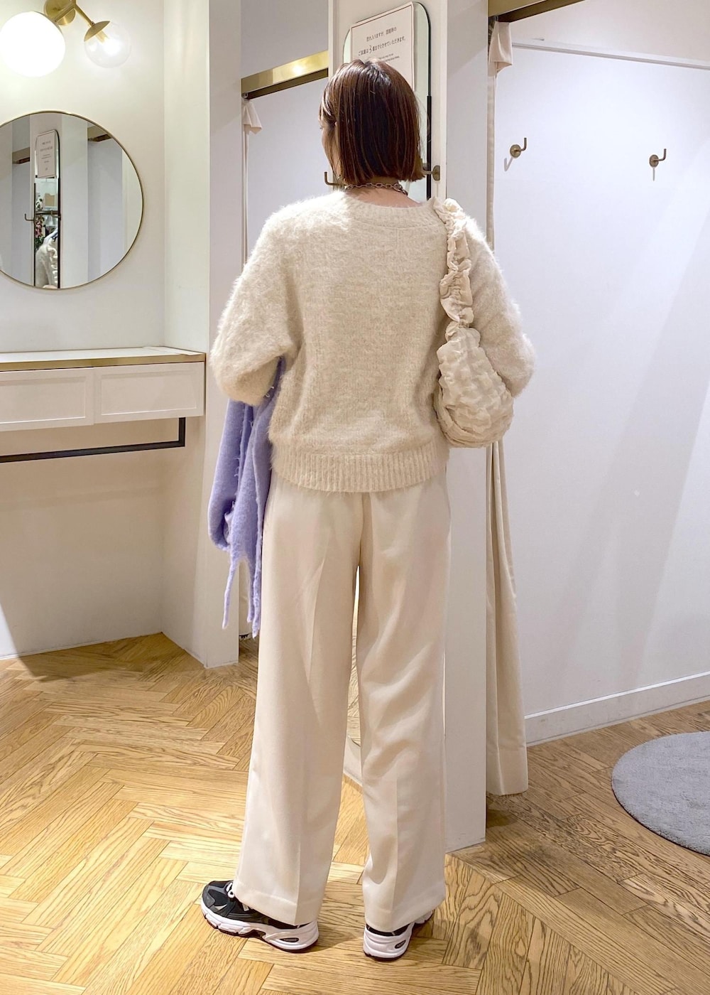 ベージュ系のニット/セーター、ホワイト系のスラックス、ホワイト系のショルダーバッグを着用したレディースの冬コーディネートの3枚目の写真
