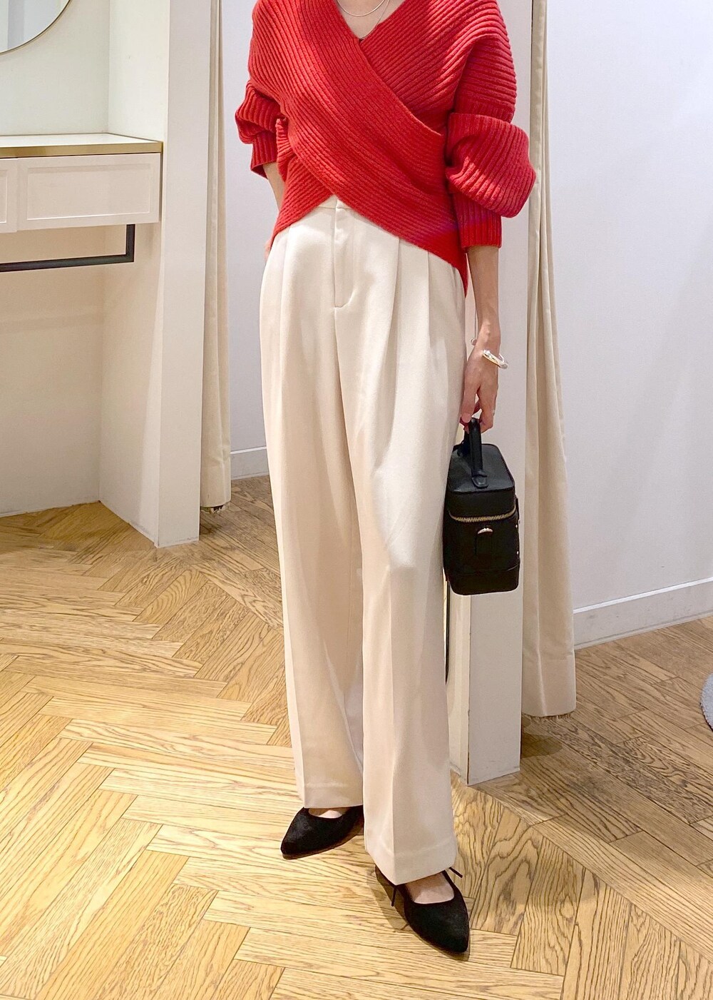 レッド系のニット/セーター、ホワイト系のスラックス、ブラック系のハンドバッグを着用したレディースの冬コーディネートの4枚目の写真