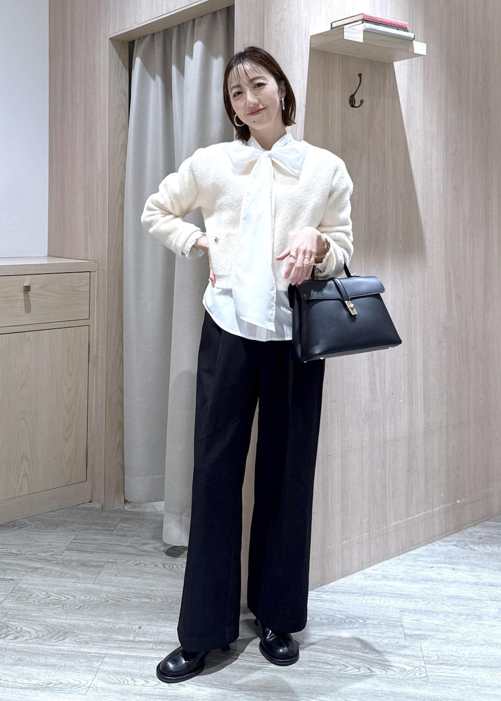 ブラック系のハンドバッグ、ブラック系のスラックス、ホワイト系のカーディガン/ボレロを着用したレディースの冬コーディネートの10枚目の写真