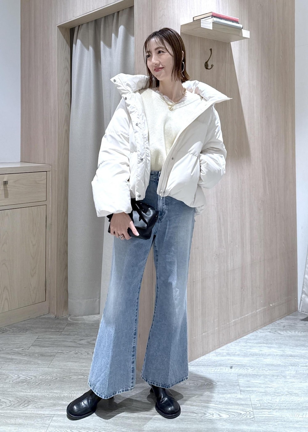 ホワイト系のダウンジャケット/コート、ブラック系のショルダーバッグ、ホワイト系のニット/セーターを着用したレディースの冬コーディネートの2枚目の写真