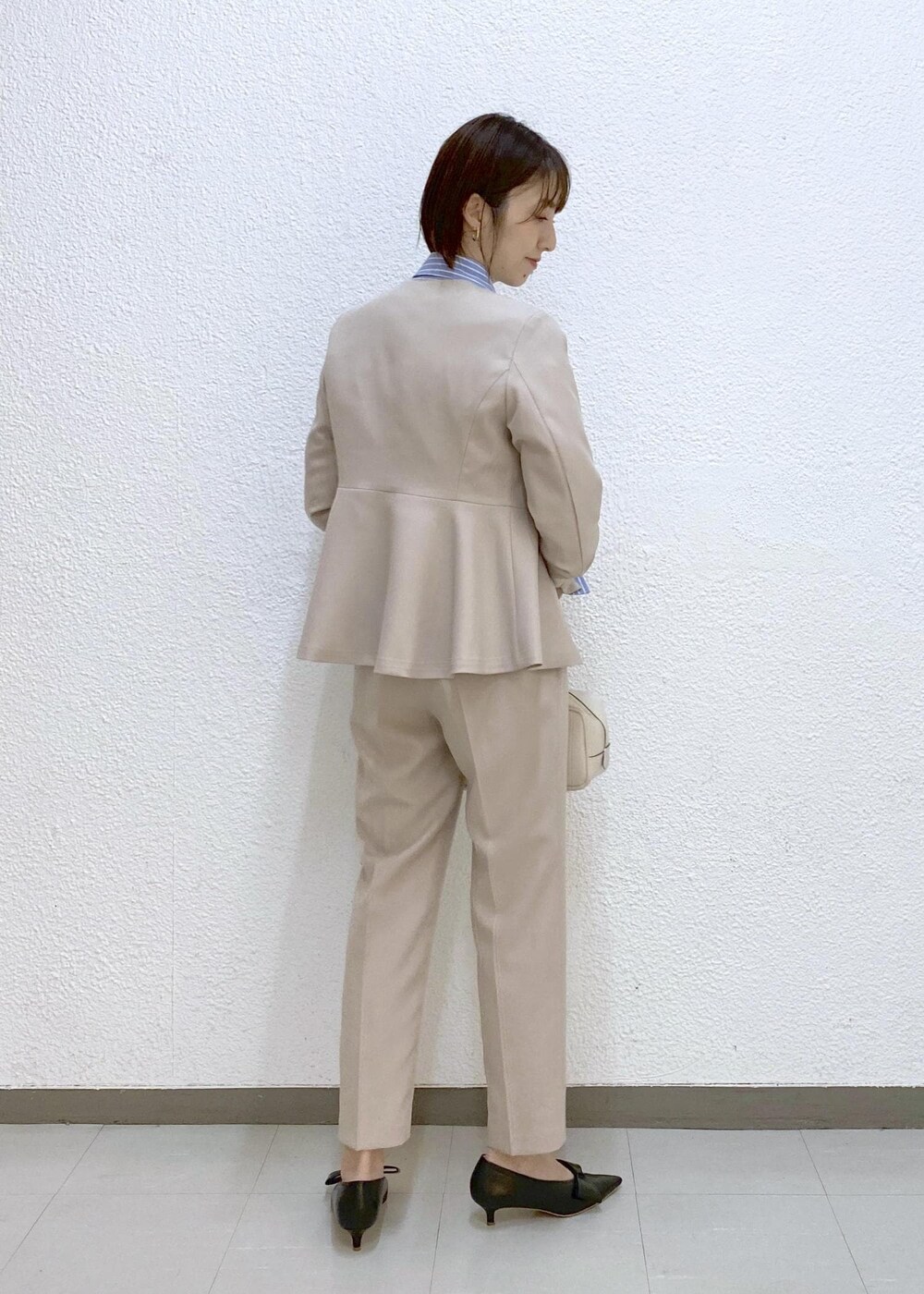 ブラック系のパンプス、ブルー系のシャツ/ブラウス、ベージュ系のノーカラージャケットを着用したレディースの冬コーディネートの2枚目の写真