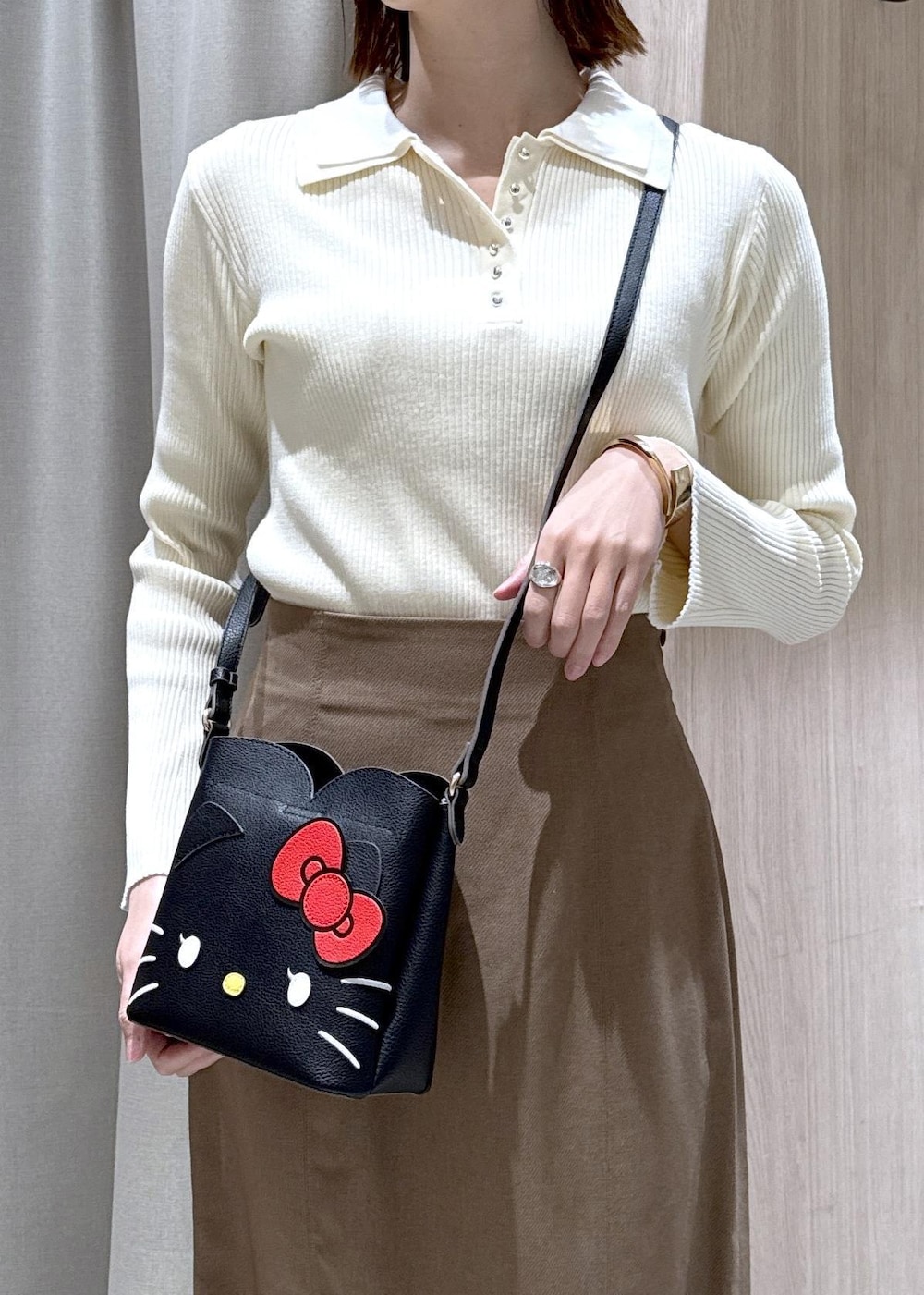 ブラウン系のスカート、ホワイト系のニット/セーター、ブラック系のショルダーバッグを着用したレディースの冬コーディネートの2枚目の写真