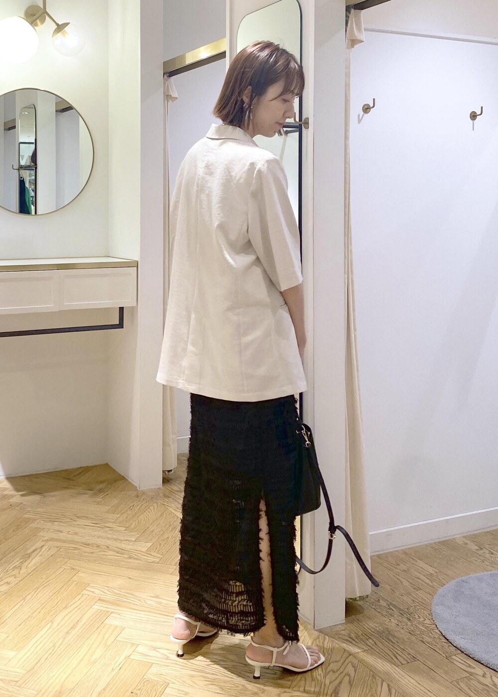 ブラック系のハンドバッグ、ホワイト系のサンダル、ホワイト系のシャツ/ブラウスを着用したレディースの春コーディネートの3枚目の写真