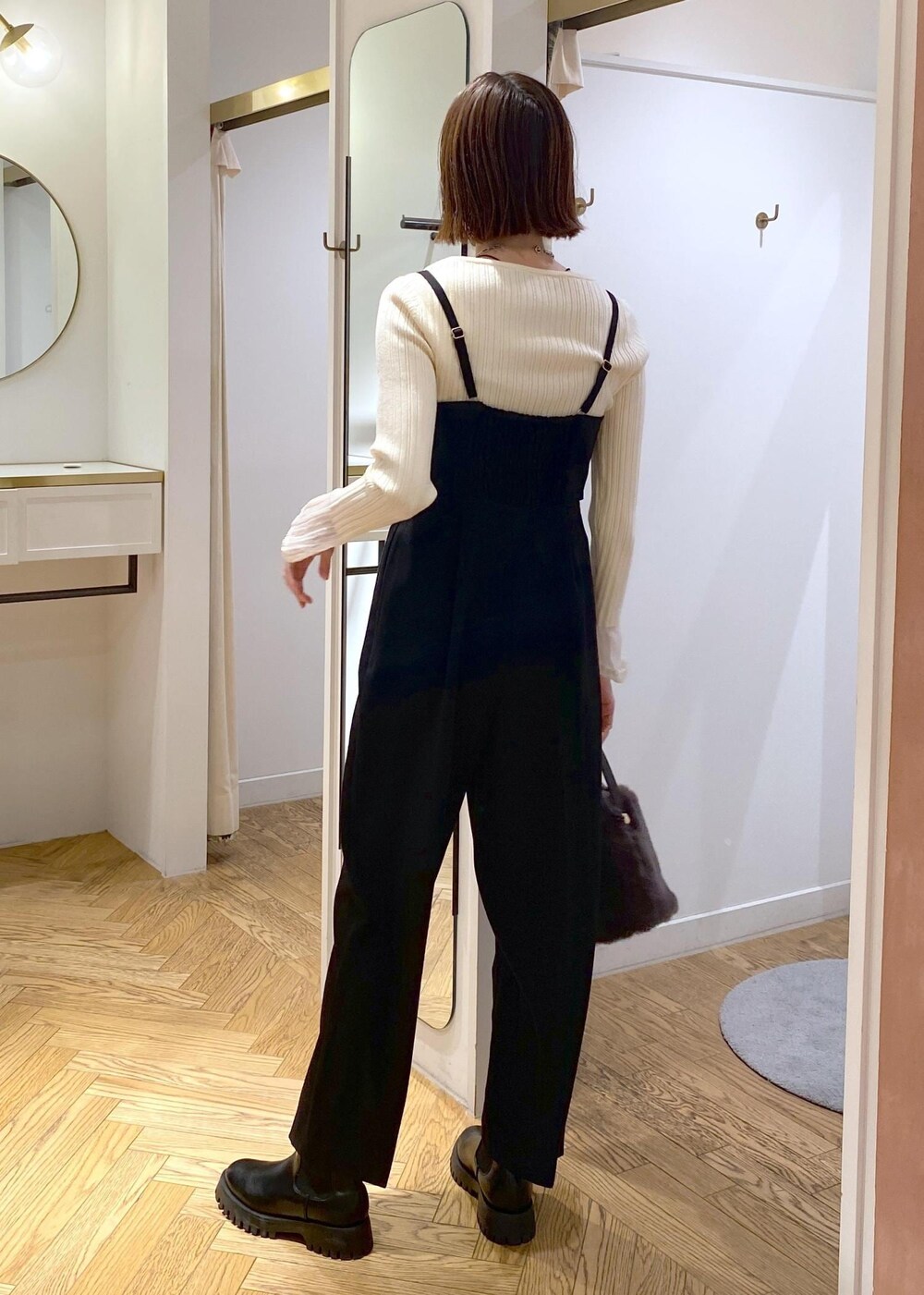 グレー系のショルダーバッグ、ブラック系のサロペット/オーバーオール、ホワイト系のニット/セーターを着用したレディースの冬コーディネートの3枚目の写真