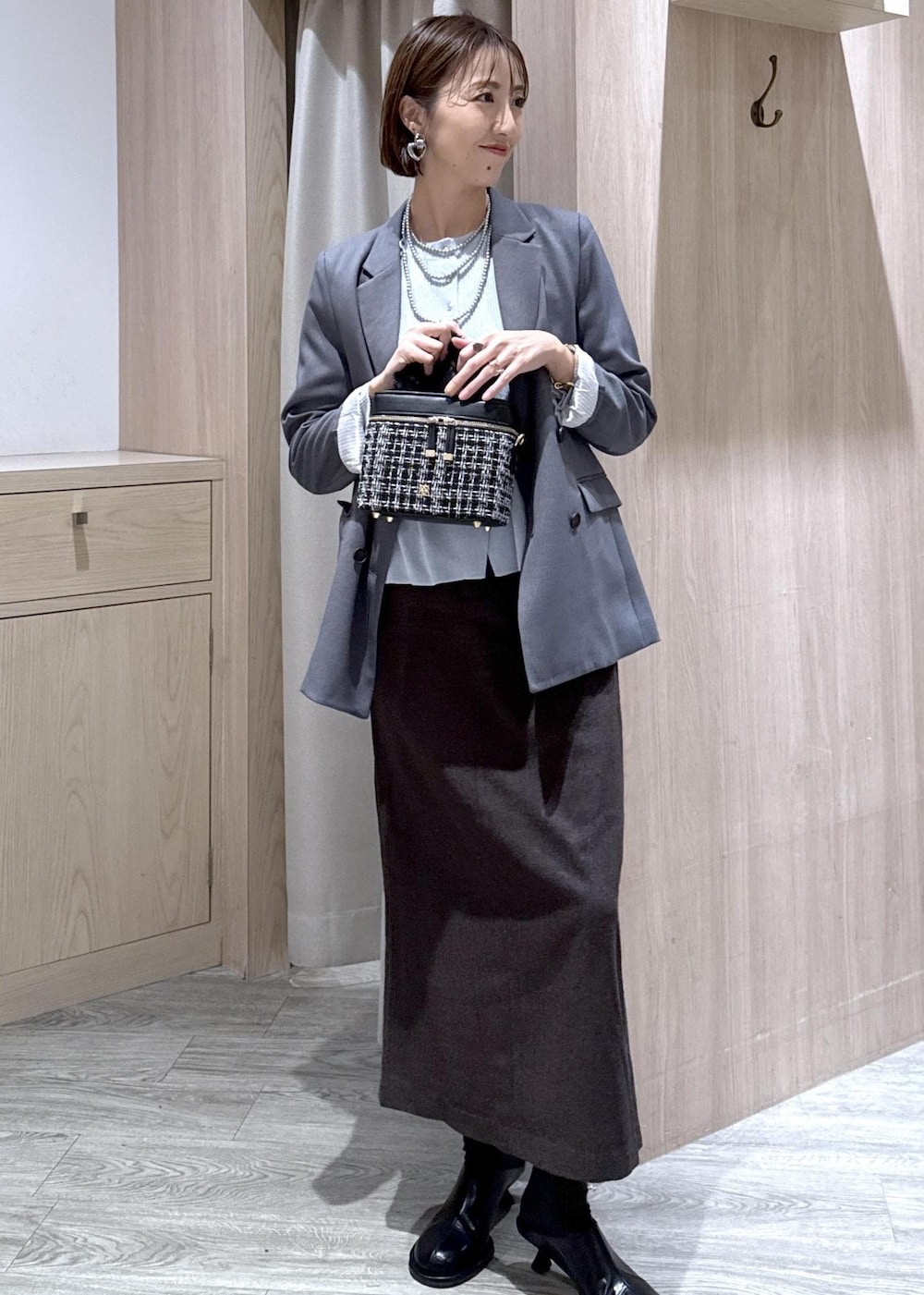 グレー系のテーラードジャケット、ブルー系のカーディガン/ボレロ、ブラウン系のスカートを着用したレディースの秋コーディネートの10枚目の写真