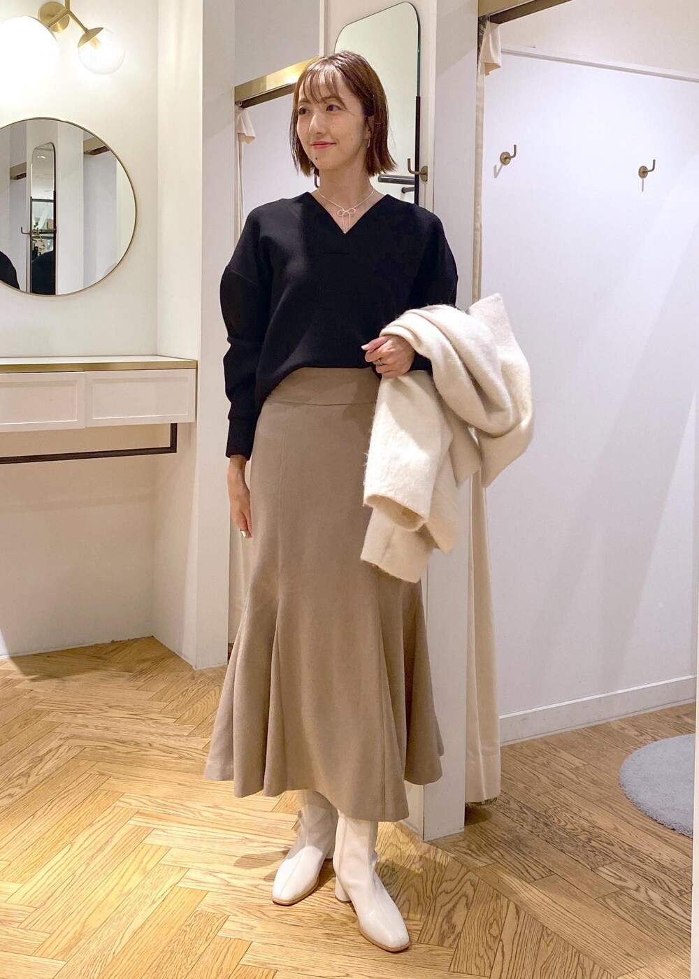 ホワイト系のブーツ、ベージュ系のスカート、ホワイト系のその他アウターを着用したレディースの秋コーディネートの9枚目の写真