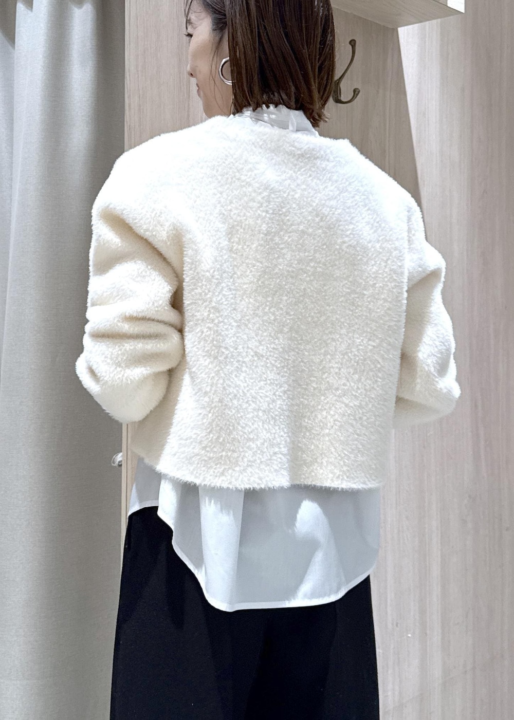 ブラック系のハンドバッグ、ブラック系のスラックス、ホワイト系のカーディガン/ボレロを着用したレディースの冬コーディネートの8枚目の写真