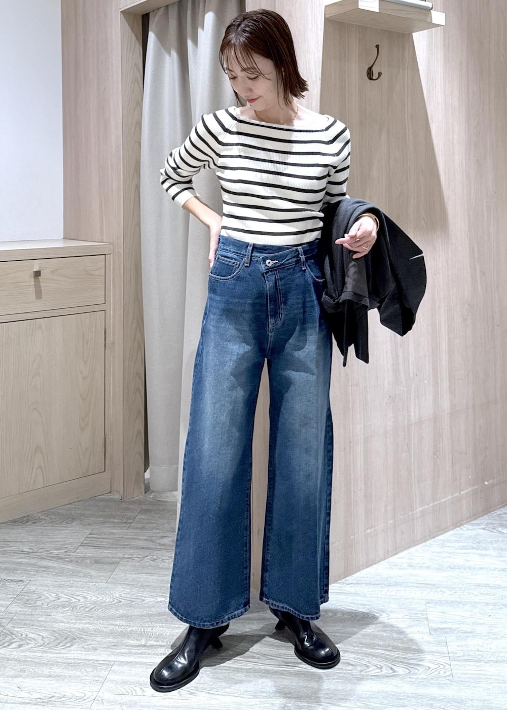 ブルー系のデニムパンツ、グレー系のテーラードジャケット、ホワイト系のショルダーバッグを着用したレディースの冬コーディネートの4枚目の写真