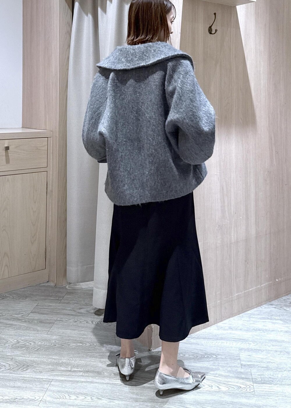 シルバー系のパンプス、ブラック系のショルダーバッグ、ブラック系のスカートを着用したレディースの冬コーディネートの2枚目の写真