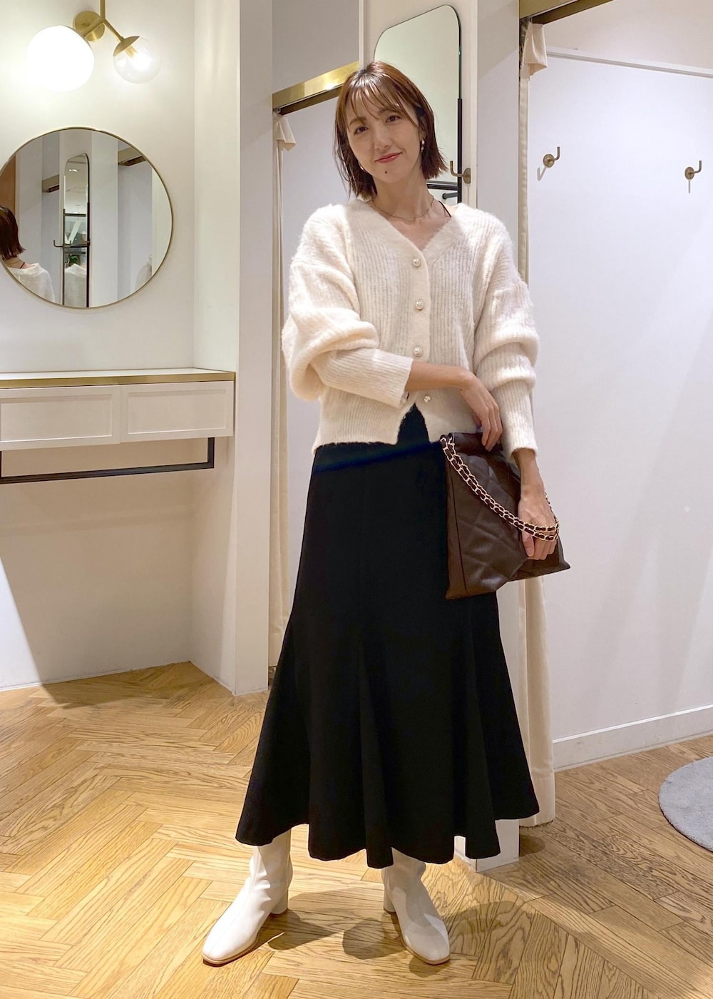 ホワイト系のブーツ、ブラック系のスカート、ブラウン系のショルダーバッグを着用したレディースの秋コーディネートの8枚目の写真