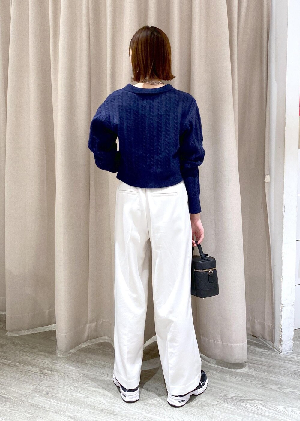 ブラック系のキャミソール、ブラック系のハンドバッグ、ホワイト系のスラックスを着用したレディースの冬コーディネートの2枚目の写真