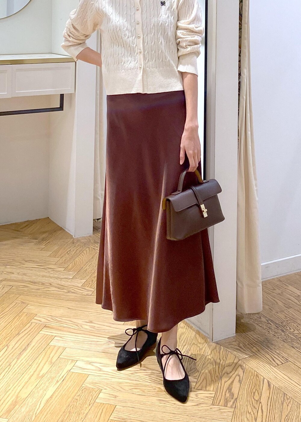 ブラウン系のスカート、ホワイト系のカーディガン/ボレロ、ブラック系のパンプスを着用したレディースの冬コーディネートの5枚目の写真