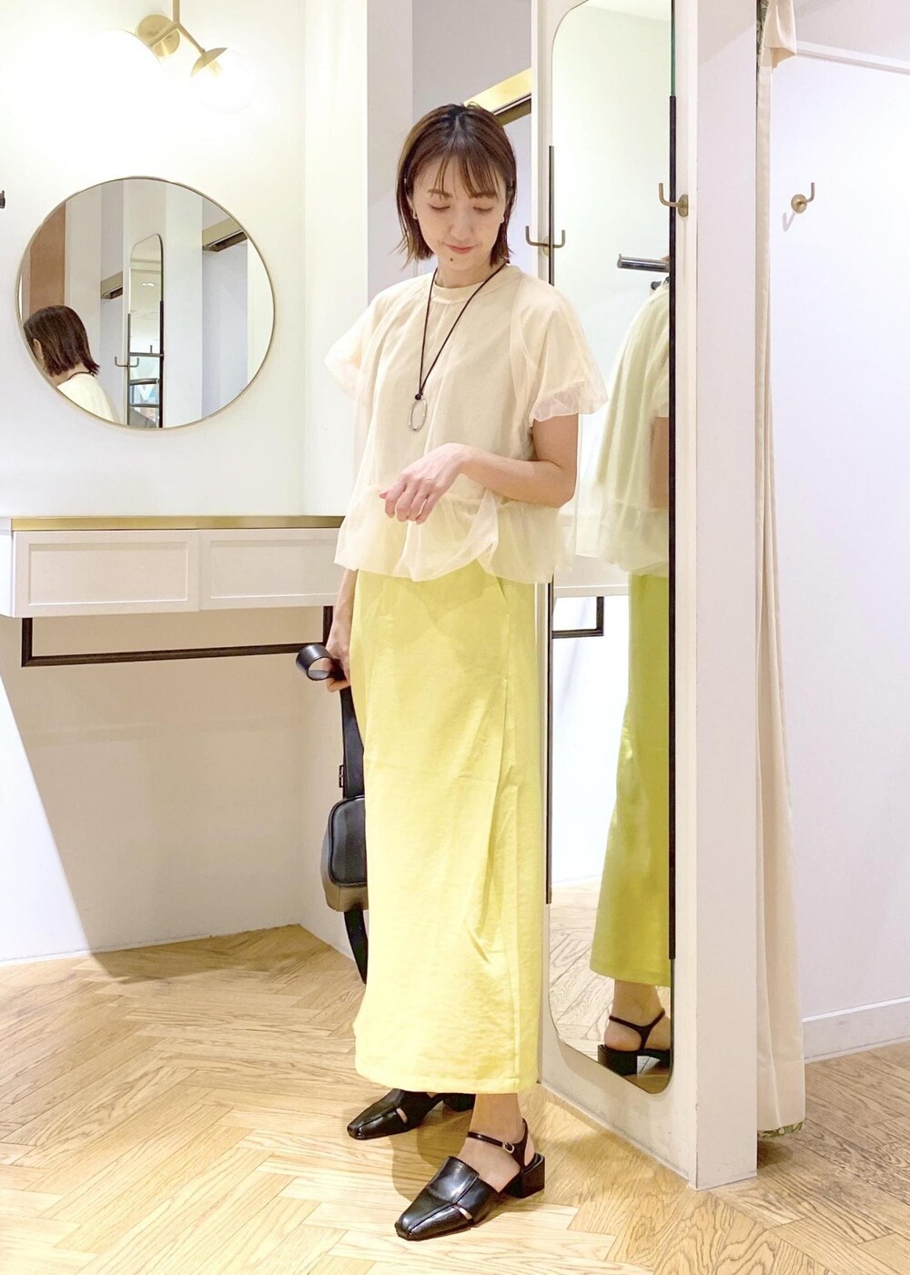 ブラック系のショルダーバッグ、ブラック系のサンダル、イエロー系のスカートを着用したレディースの春コーディネートの4枚目の写真