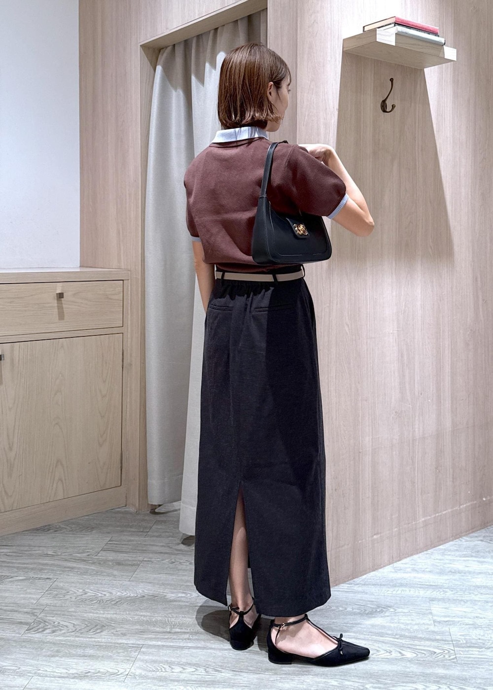 ブラック系のハンドバッグ、グレー系のスカート、ブラック系のパンプスを着用したレディースの夏コーディネートの4枚目の写真