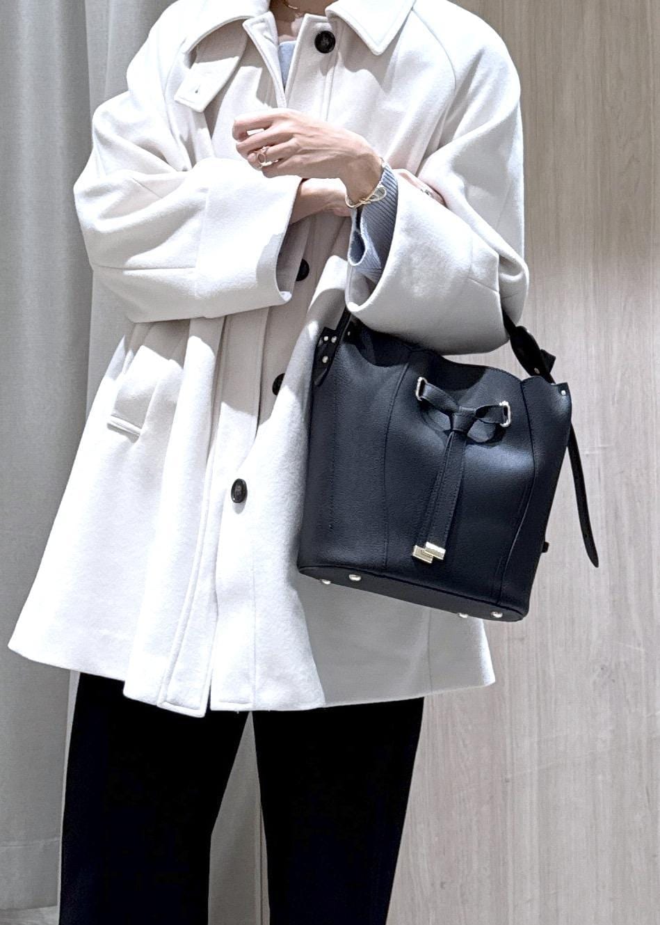 ブラック系のスラックス、ブラック系のショルダーバッグ、ブルー系のニット/セーターを着用したレディースの秋コーディネートの8枚目の写真