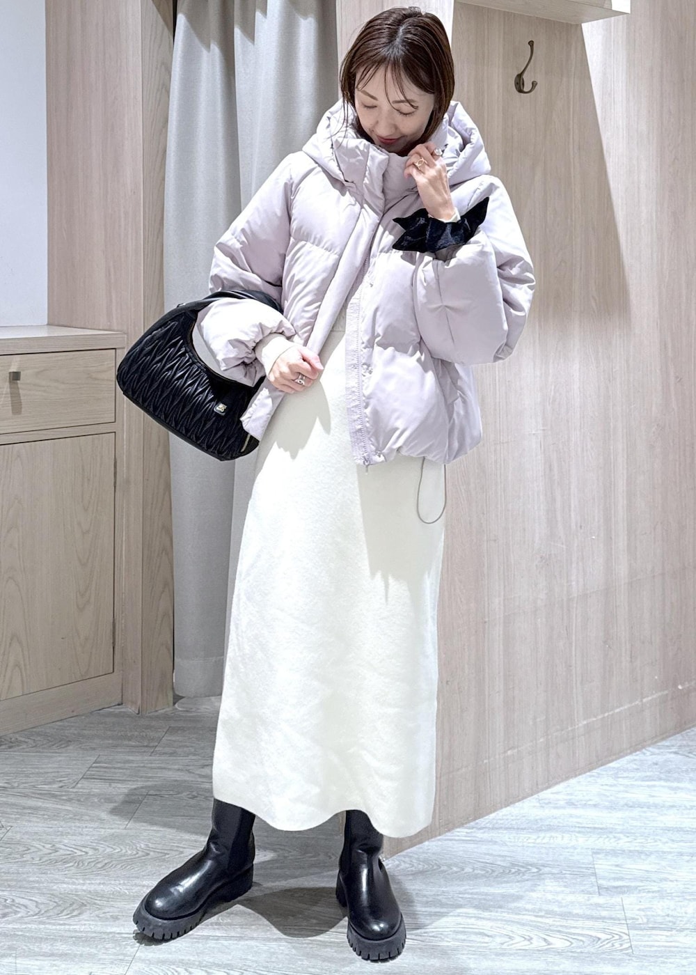 ブラック系のハンドバッグ、ピンク系のダウンジャケット/コート、ホワイト系のワンピースを着用したレディースの冬コーディネートの6枚目の写真