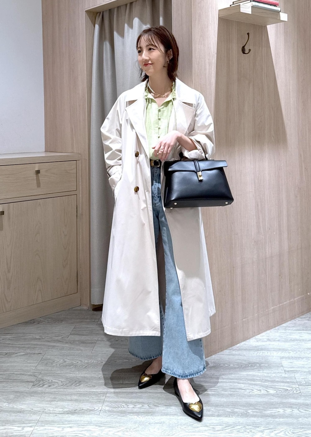ブラック系のハンドバッグ、ブラック系のバレエシューズ、ホワイト系のトレンチコートを着用したレディースの春コーディネートの2枚目の写真