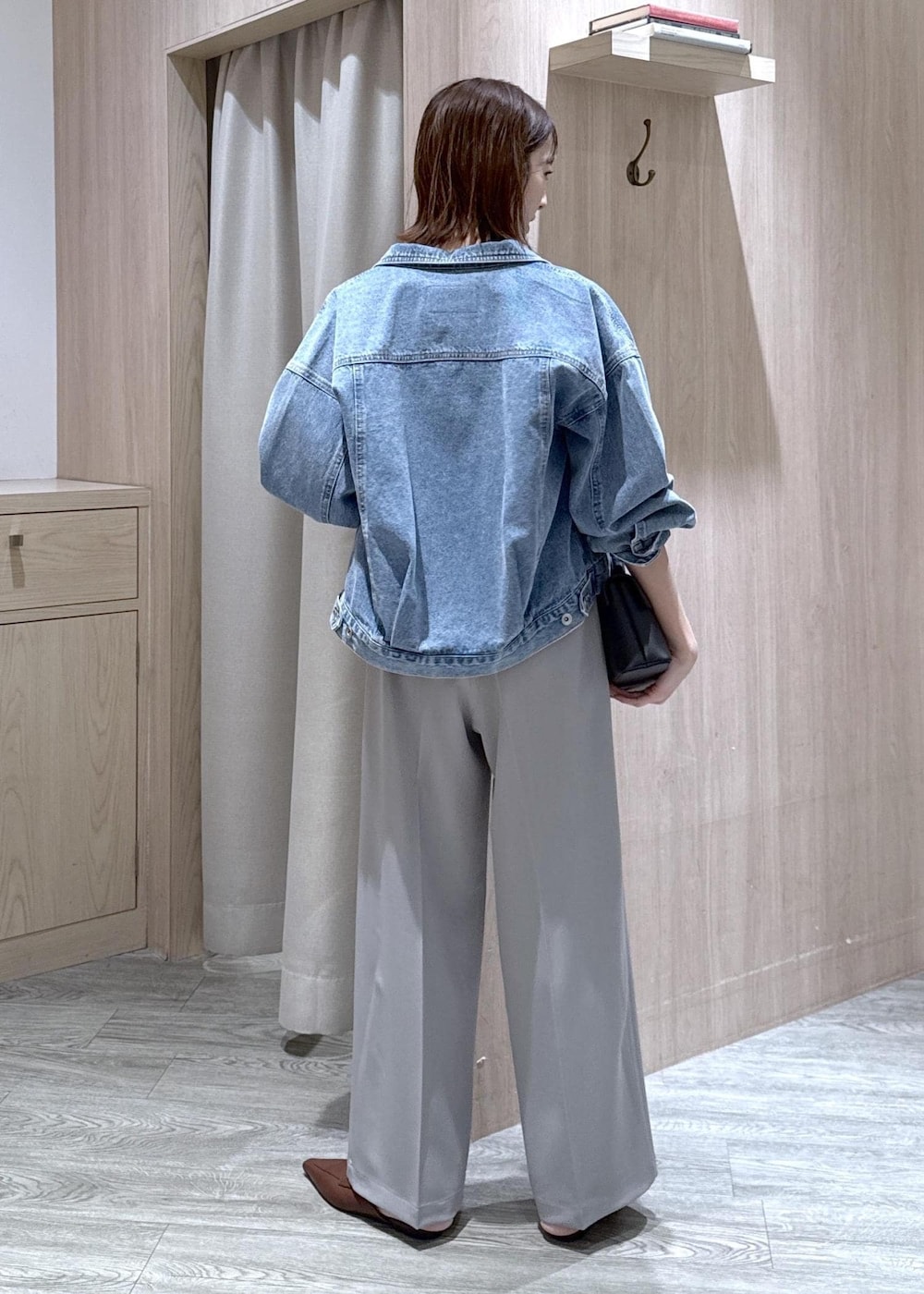 ブラック系のショルダーバッグ、ブルー系のデニムジャケット、グレー系のスラックスを着用したレディースの春コーディネートの4枚目の写真