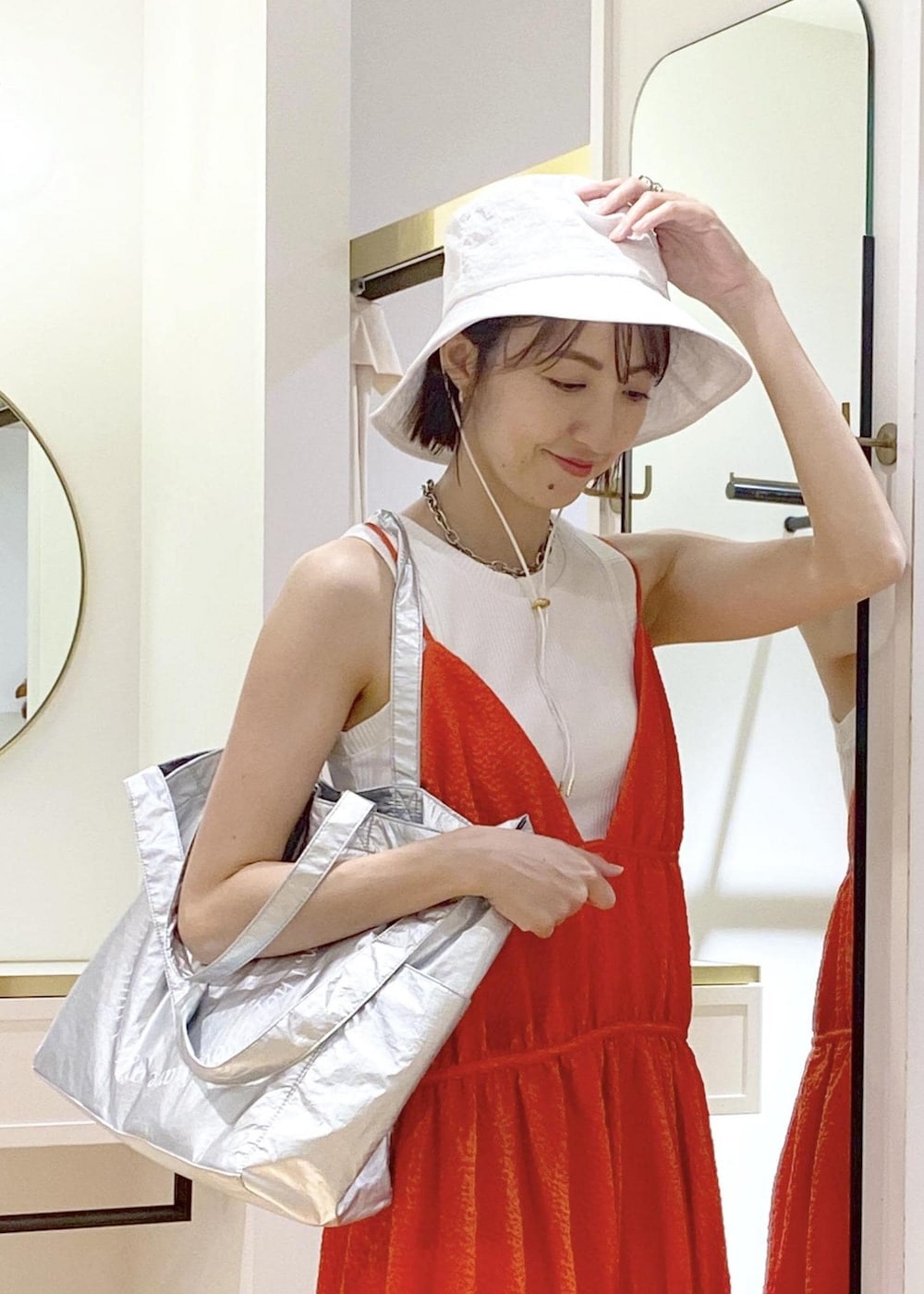 ブラック系のサンダル、オレンジ系のジャンパースカート、ホワイト系のタンクトップを着用したレディースの春コーディネートの4枚目の写真