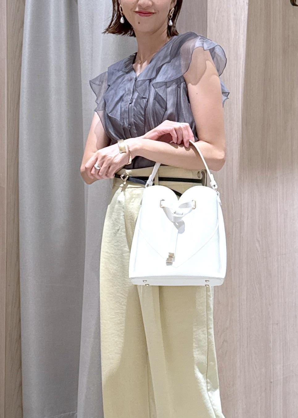 ホワイト系のショルダーバッグ、ホワイト系のサンダル、イエロー系のスラックスを着用したレディースの夏コーディネートの5枚目の写真