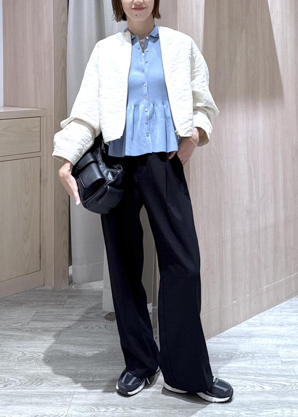 ブラック系のスラックス、ブラック系のショルダーバッグ、ブルー系のカーディガン/ボレロを着用したレディースの秋コーディネートの2枚目の写真