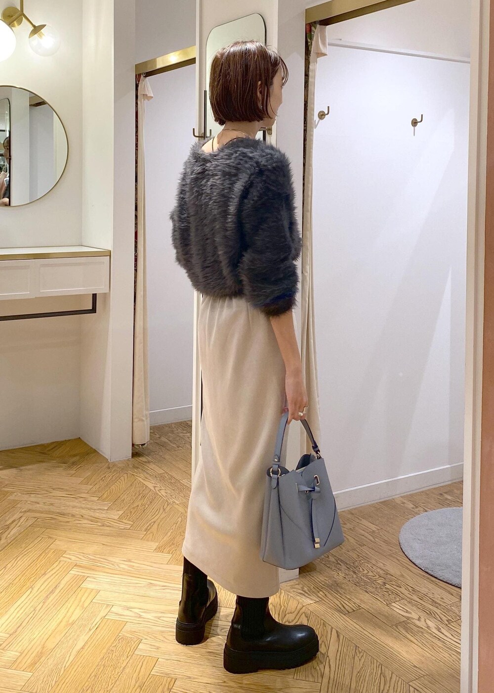 ブラック系のブーツ、ベージュ系のスカート、グレー系のカーディガン/ボレロを着用したレディースの冬コーディネートの3枚目の写真