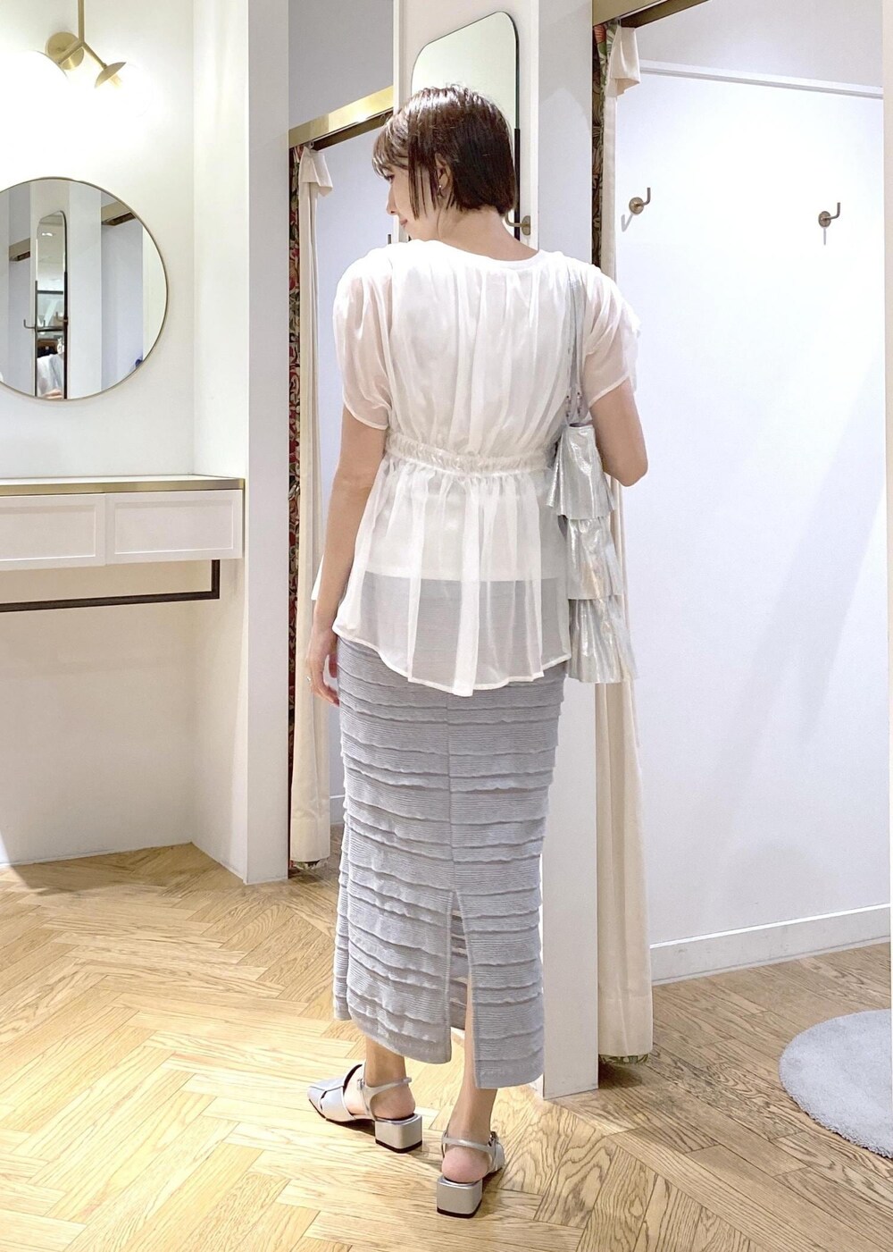 シルバー系のサンダル、シルバー系のトートバッグ、ホワイト系のTシャツ/カットソーを着用したレディースの夏コーディネートの3枚目の写真