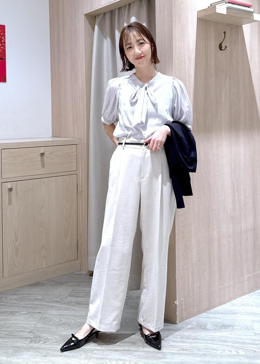 ブラック系のハンドバッグ、ブラック系のカーディガン/ボレロ、ブラック系のパンプスを着用したレディースの春コーディネートの6枚目の写真